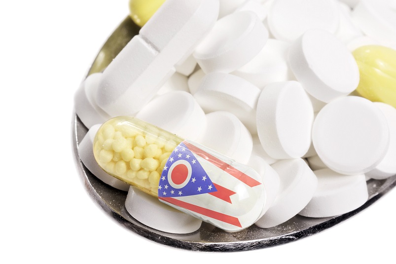 The national flag of Ohio on a capsule and pills on a spoon