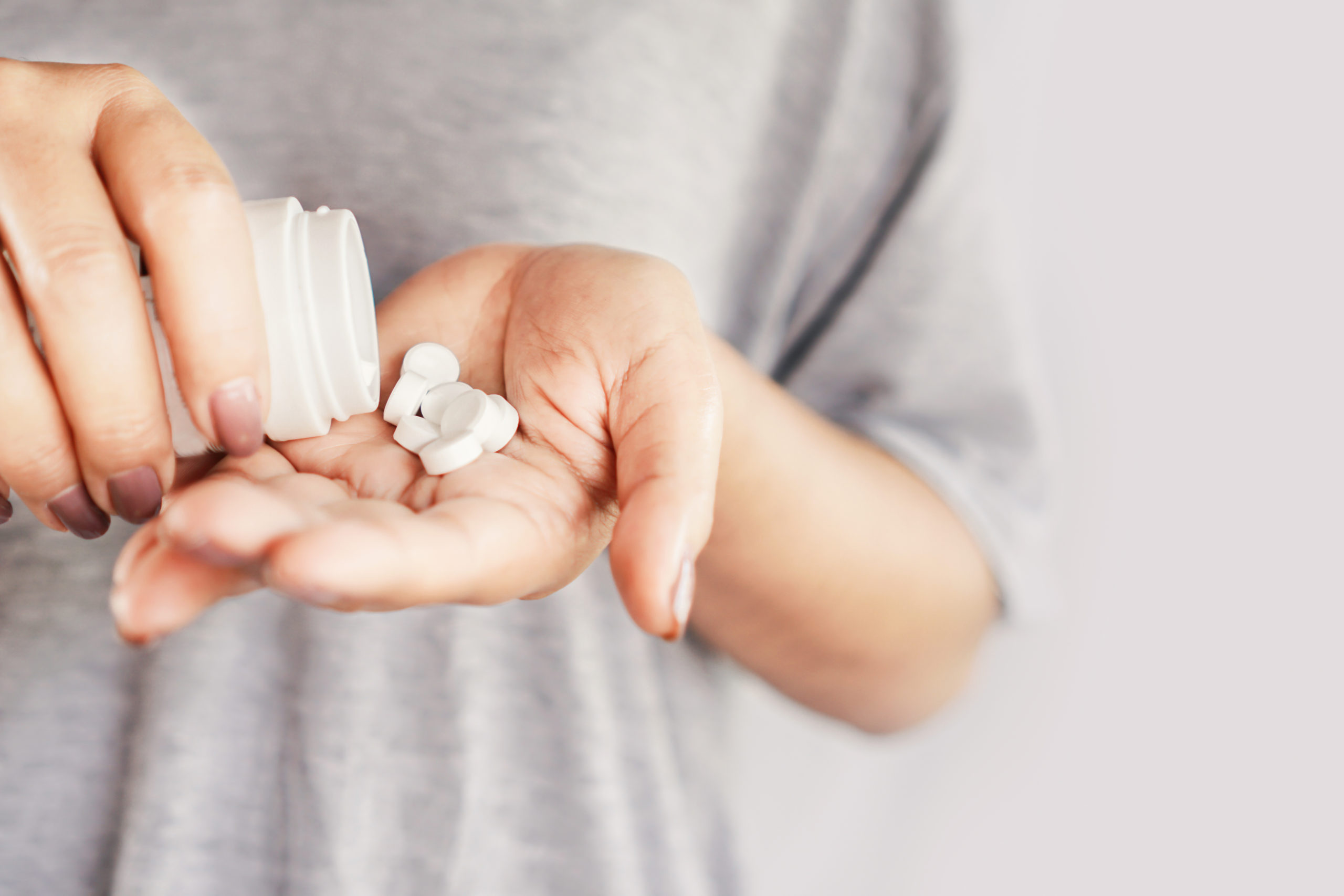 addicted women holding several white pills